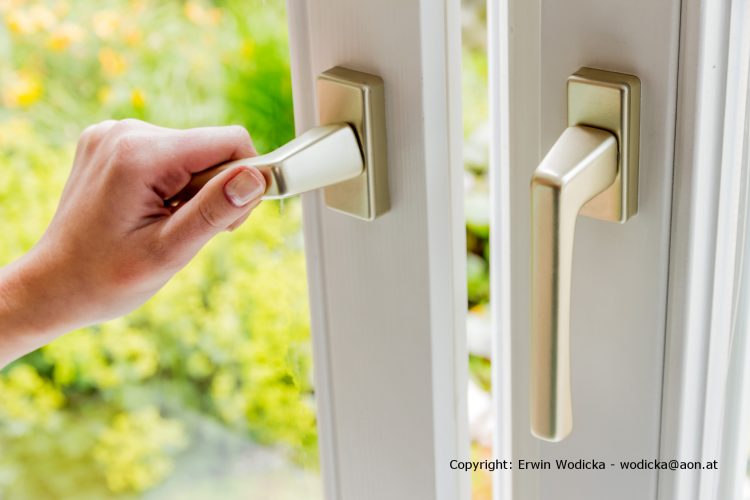 Eine Frau öffnet ein Fenster zum Lüften der Wohnung. Frische Luft im Zimmer